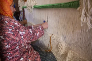 Master weaver at Berber Creations workshop in the Atlas Mountains hand-knotting a traditional Beni Ourain rug