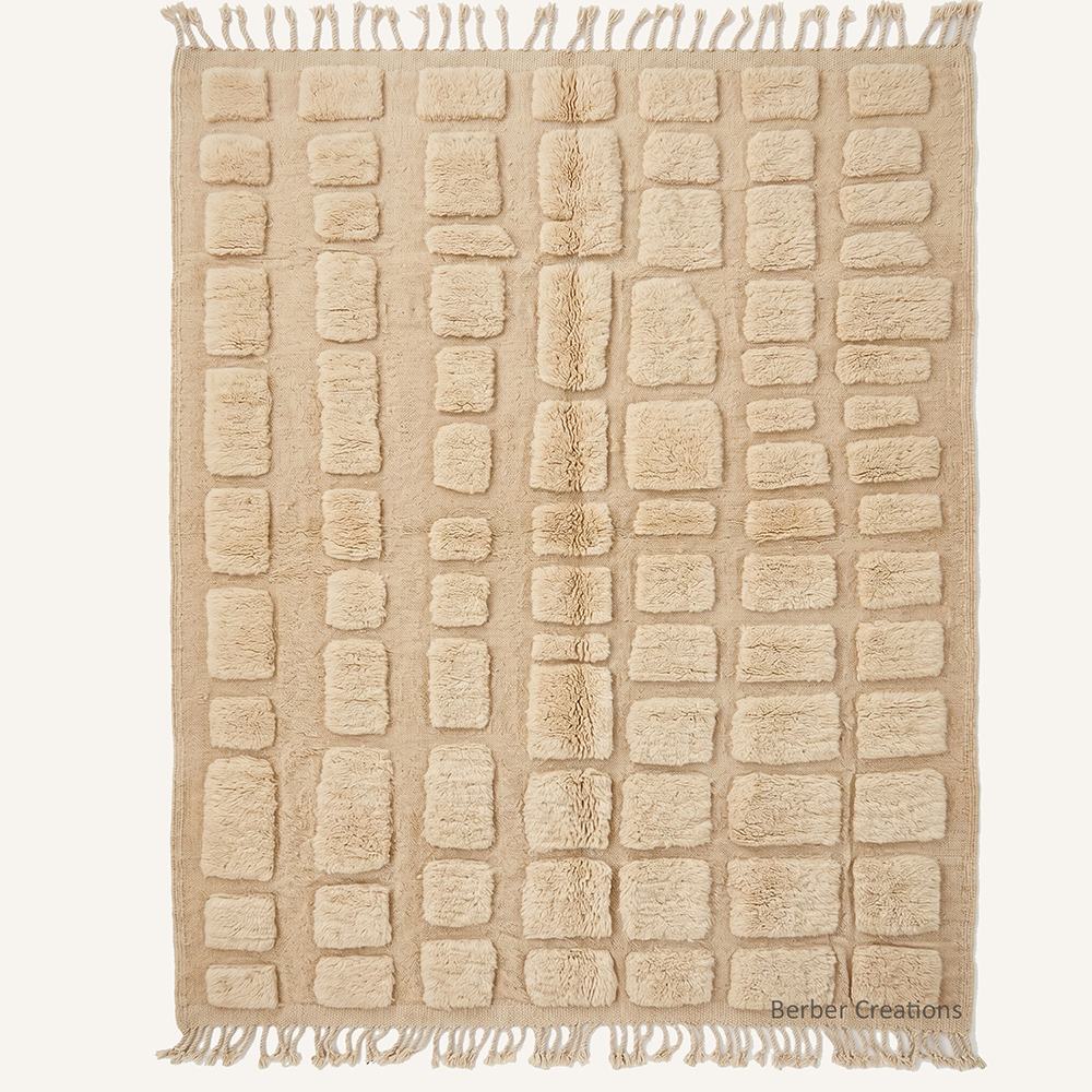 The Saharan Pavé: High-pile sand-beige Beni Mrirt rug with 3D carved embossed block pattern, handmade from organic wool in our Moroccan workshop.