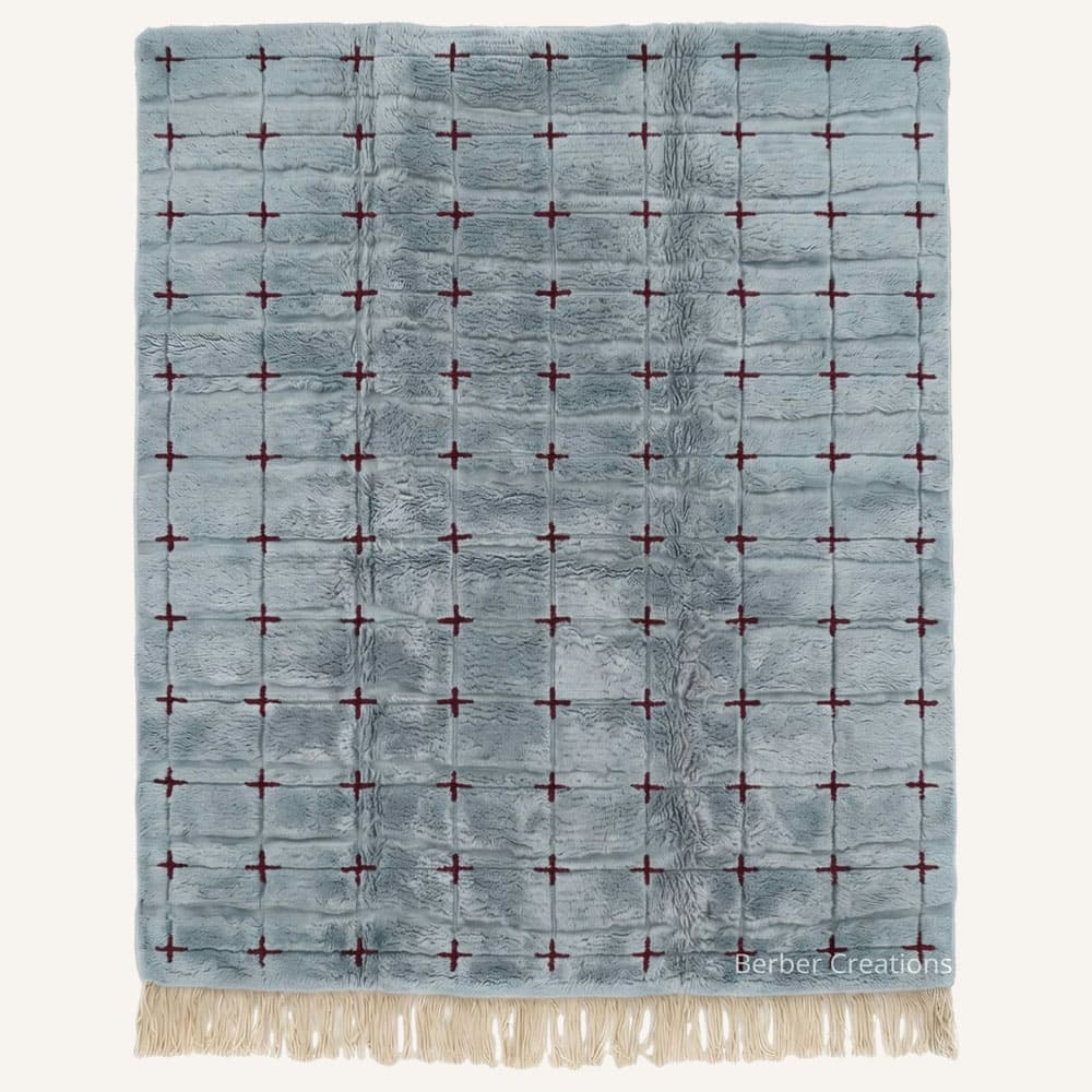 Ifri handmade Moroccan Berber wool rug featuring a plush dusty blue field structured by a subtle geometric grid with small burgundy cross motifs and braided natural fringe at the bottom edge