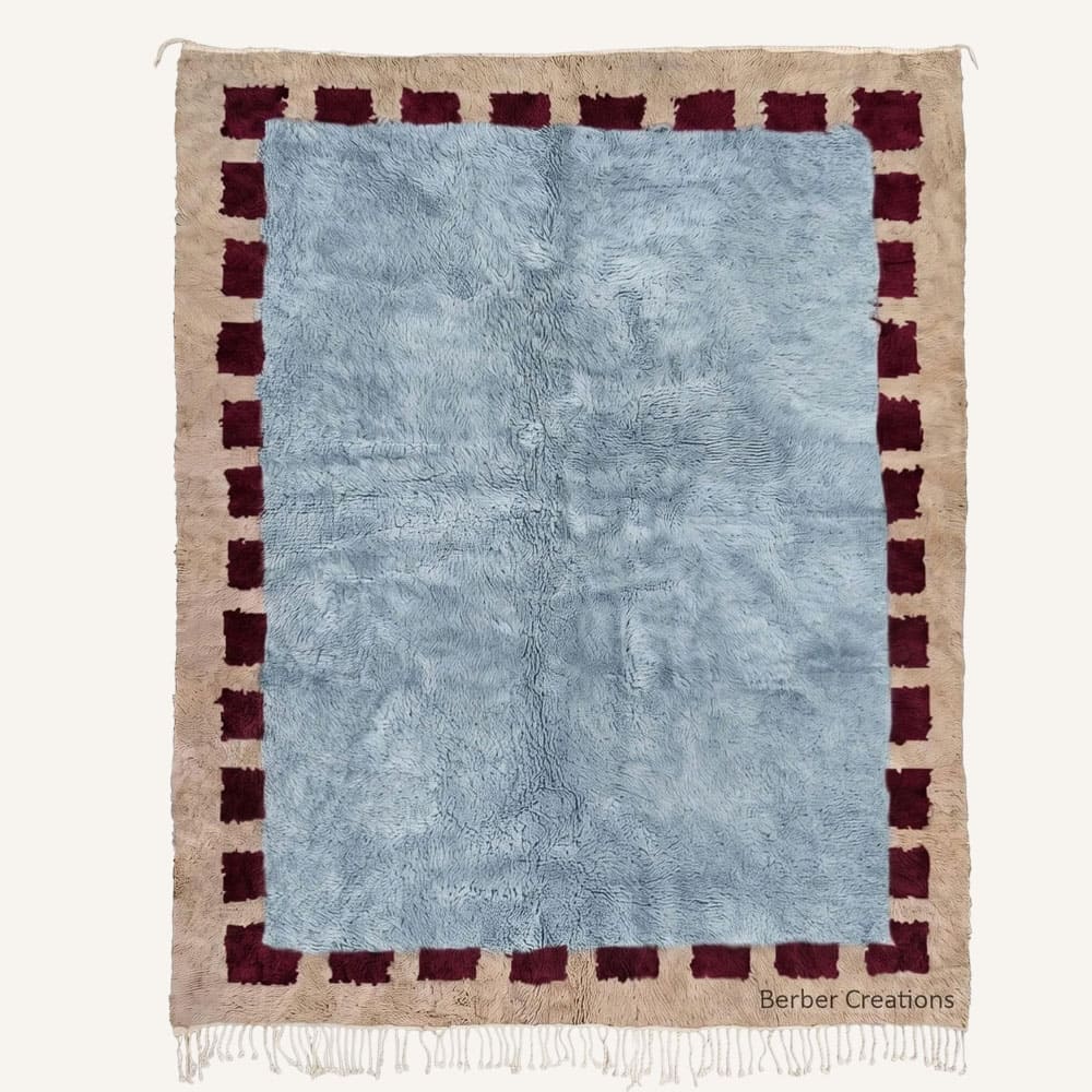 Amddaw handmade Moroccan Berber wool rug featuring a central plush dusty slate blue field enclosed by a deep burgundy dashed block inner border on an oatmeal beige outer selvedge