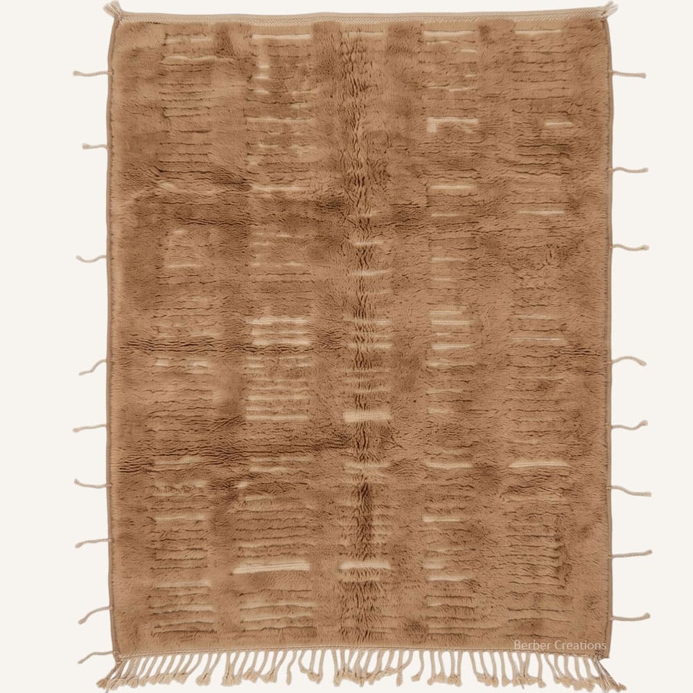 Flat lay overhead view of the Amddaw handmade Moroccan Berber wool rug featuring a plush warm camel brown pile carved with vertical column grids, cream accent dashes, and side-fringe tassels with braided bottom fringe