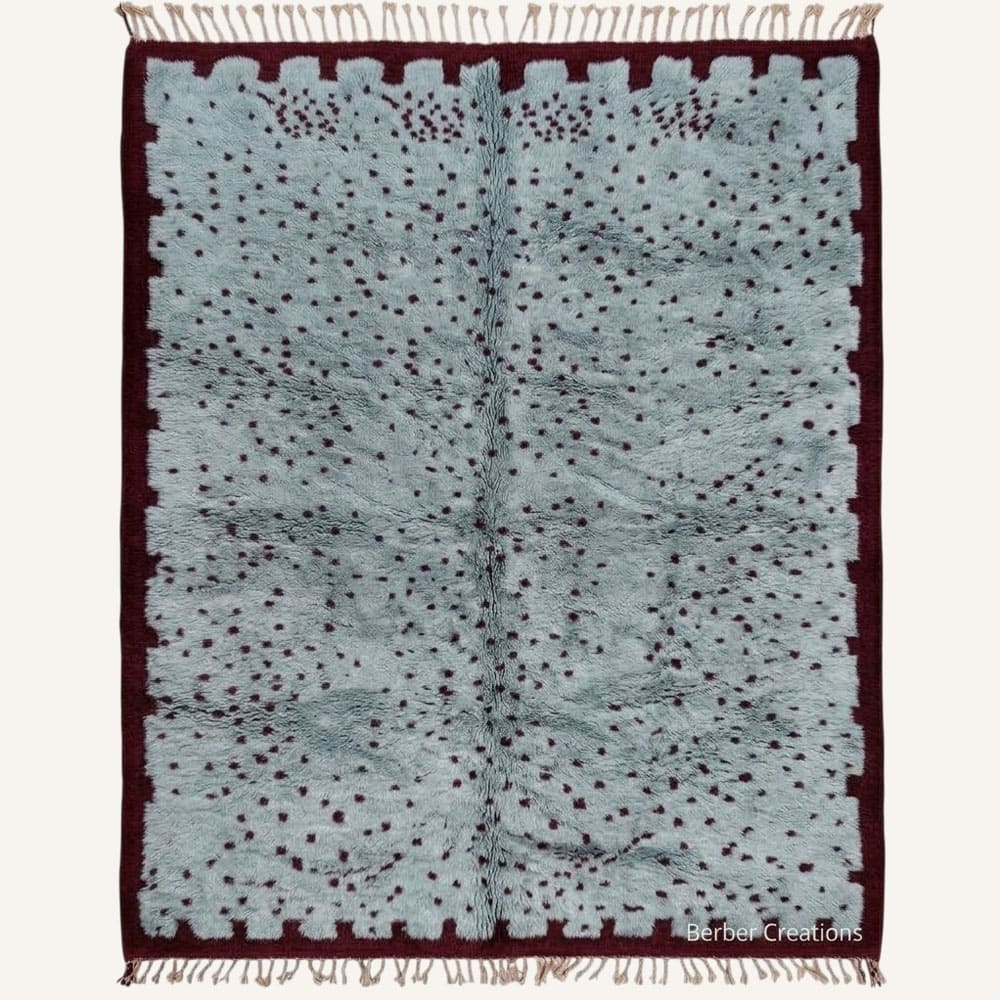 Itran handmade Moroccan Berber wool rug featuring a plush dusty slate blue field filled with fine deep burgundy speckled motifs, framed by a notched burgundy border