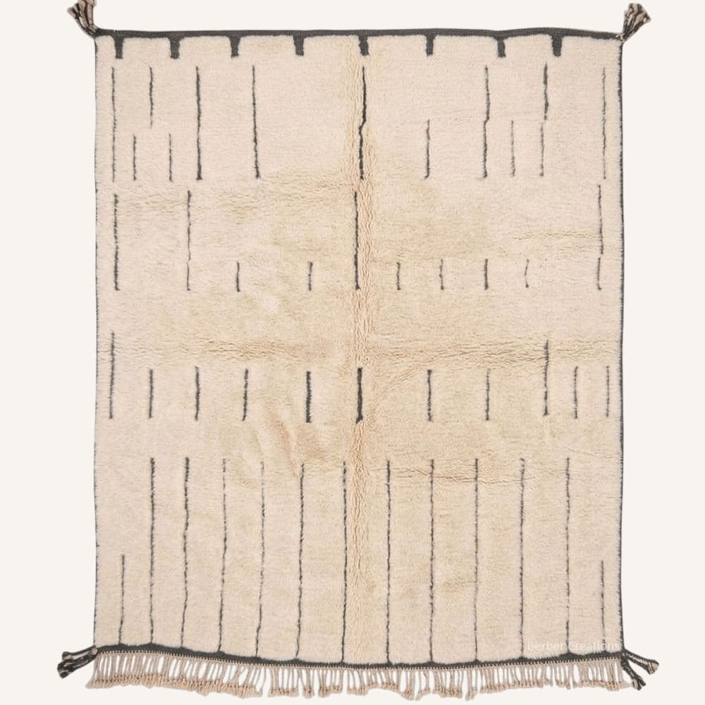 Titrit handmade Moroccan Berber wool rug featuring an open cream plush wool field with broken charcoal pinstripes, framed top and bottom selvedges, braided bottom fringe